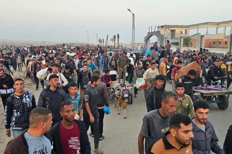 Displaced Palestinians return from a food distribution hub in Rafah, southern Gaza [AFP]